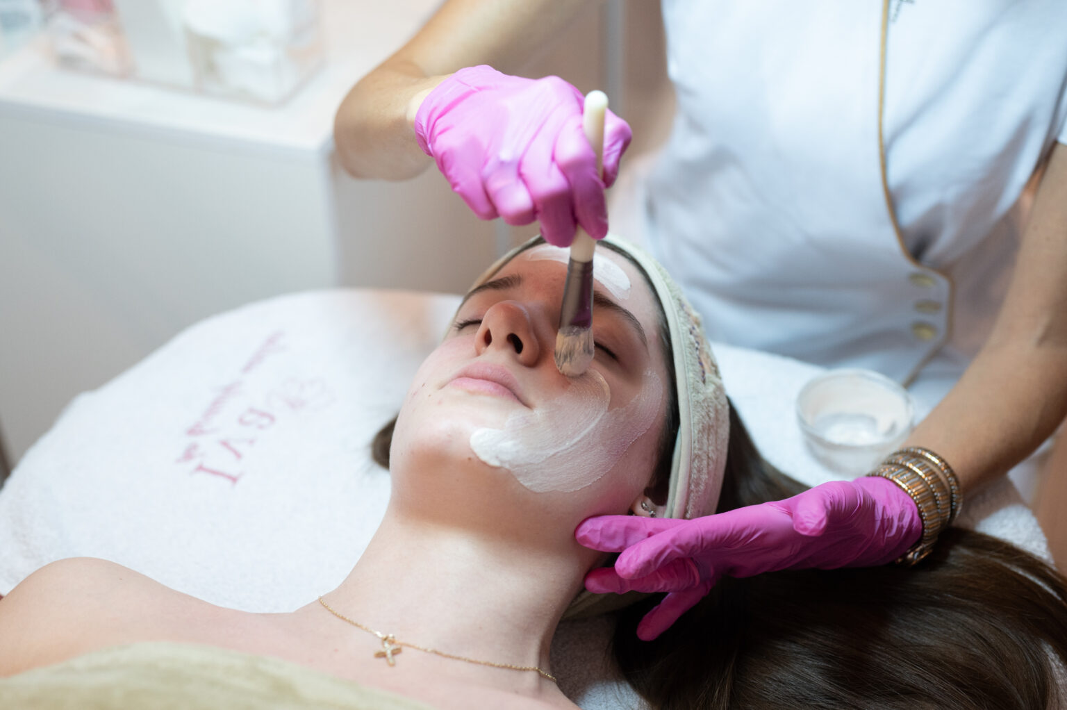 Lydia Esthetics Embassy A person receives a facial treatment as a professional applies a white cream mask using a brush, experiencing the luxury of Biologique Recherche facials New York is known for. New York