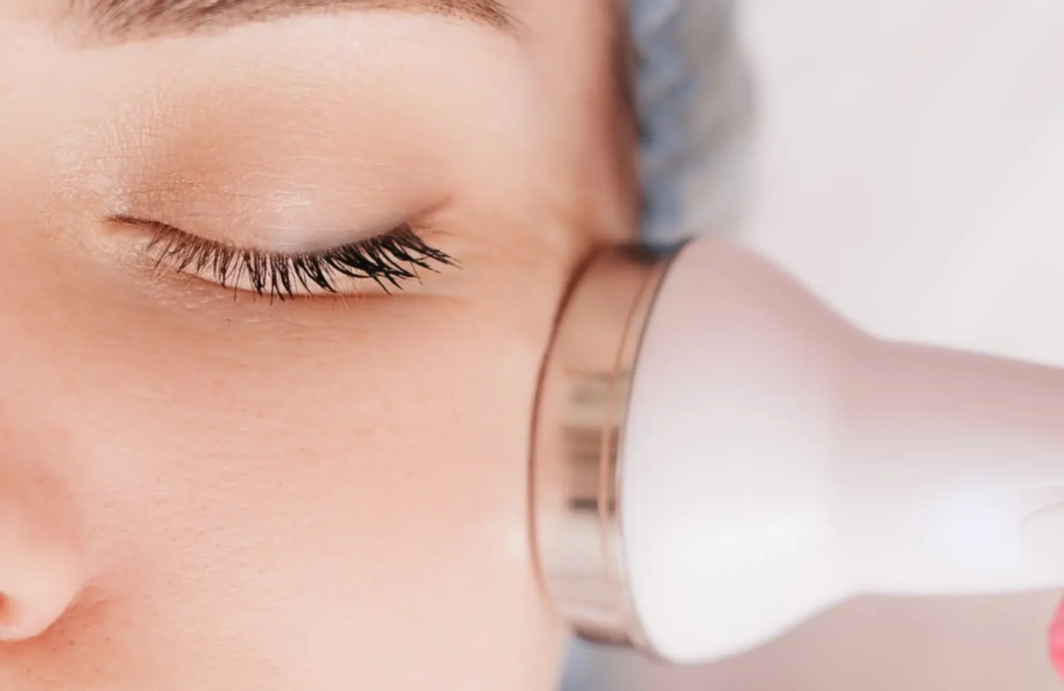Lydia Esthetics Embassy Close-up of a person with closed eyes receiving a facial treatment using a handheld skincare device on their cheek. New York