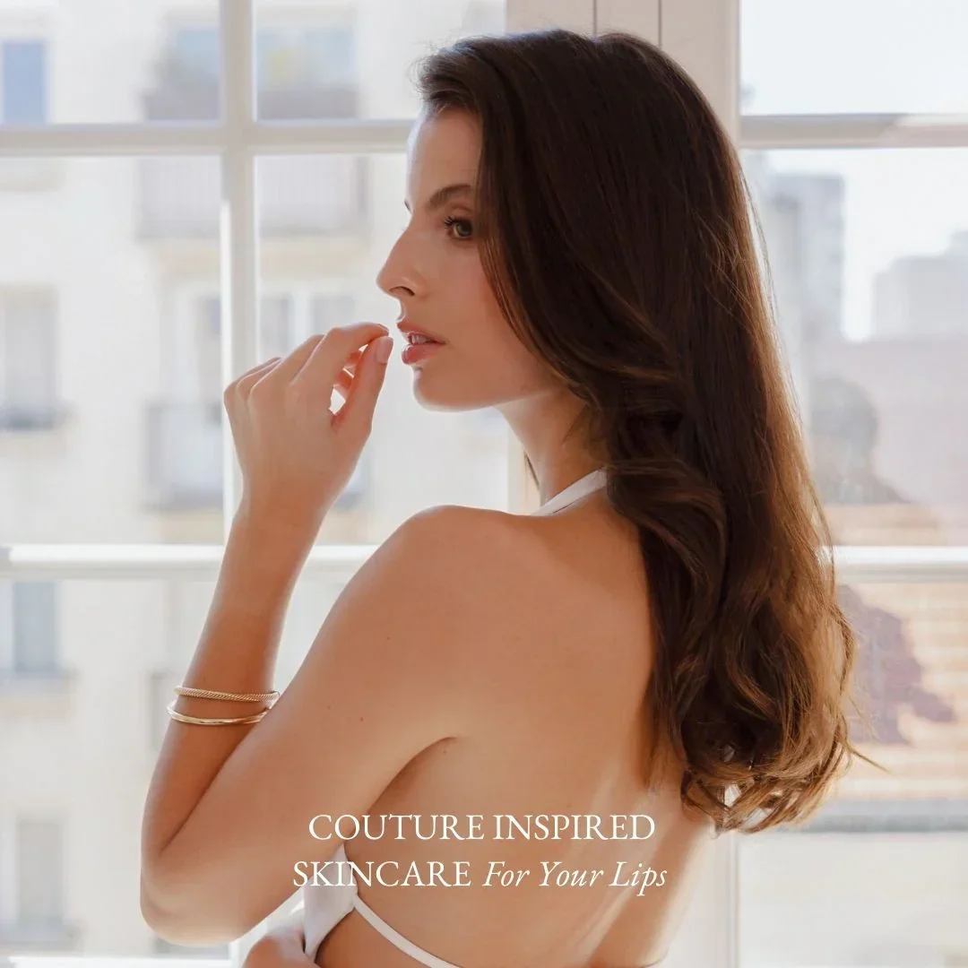 Lydia Esthetics Embassy A woman with long brown hair poses indoors by a window, looking to the side. Text on image reads: "Couture inspired skincare for your lips. New York
