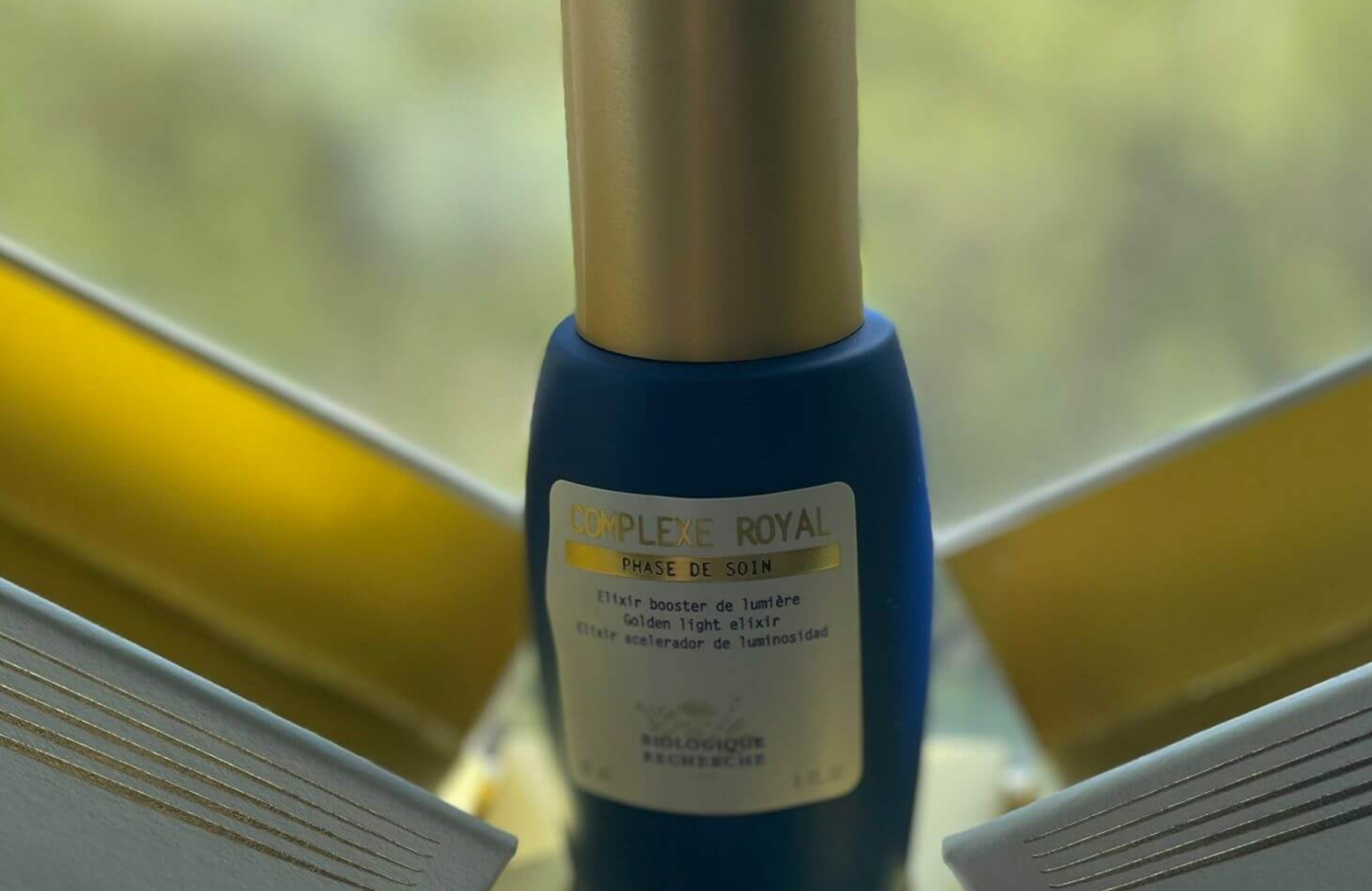 Lydia Esthetics Embassy A bottle of Biologique Recherche Complexe Royal serum, renowned for its proactive sensitive skin care benefits, is placed in front of an open book with a blurred background. New York